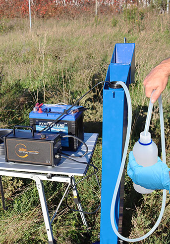 field person taking groundwater samples using solinst 12v submersible pump at groundwater monitoring well